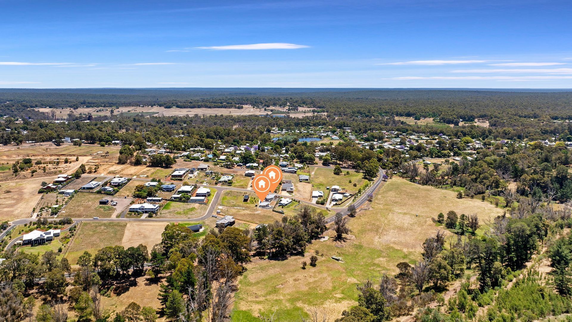 An aerial view of a residential area with houses, roads, and surrounding greenery.