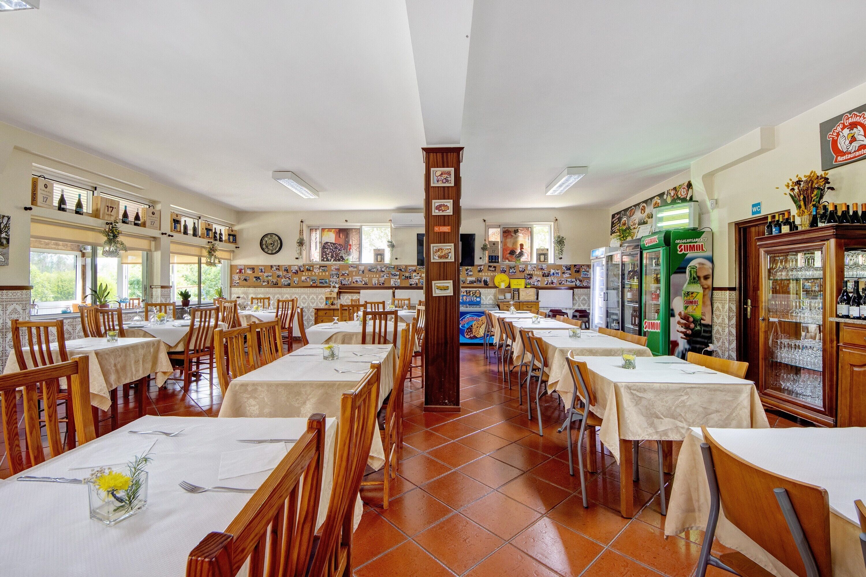Un restaurant doté de nombreuses tables, de chaises et d’un bar où sont exposées des bouteilles et des verres.
