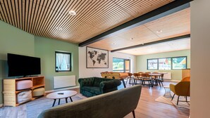 A modern living room with a television, seating, a world map, and a dining area.