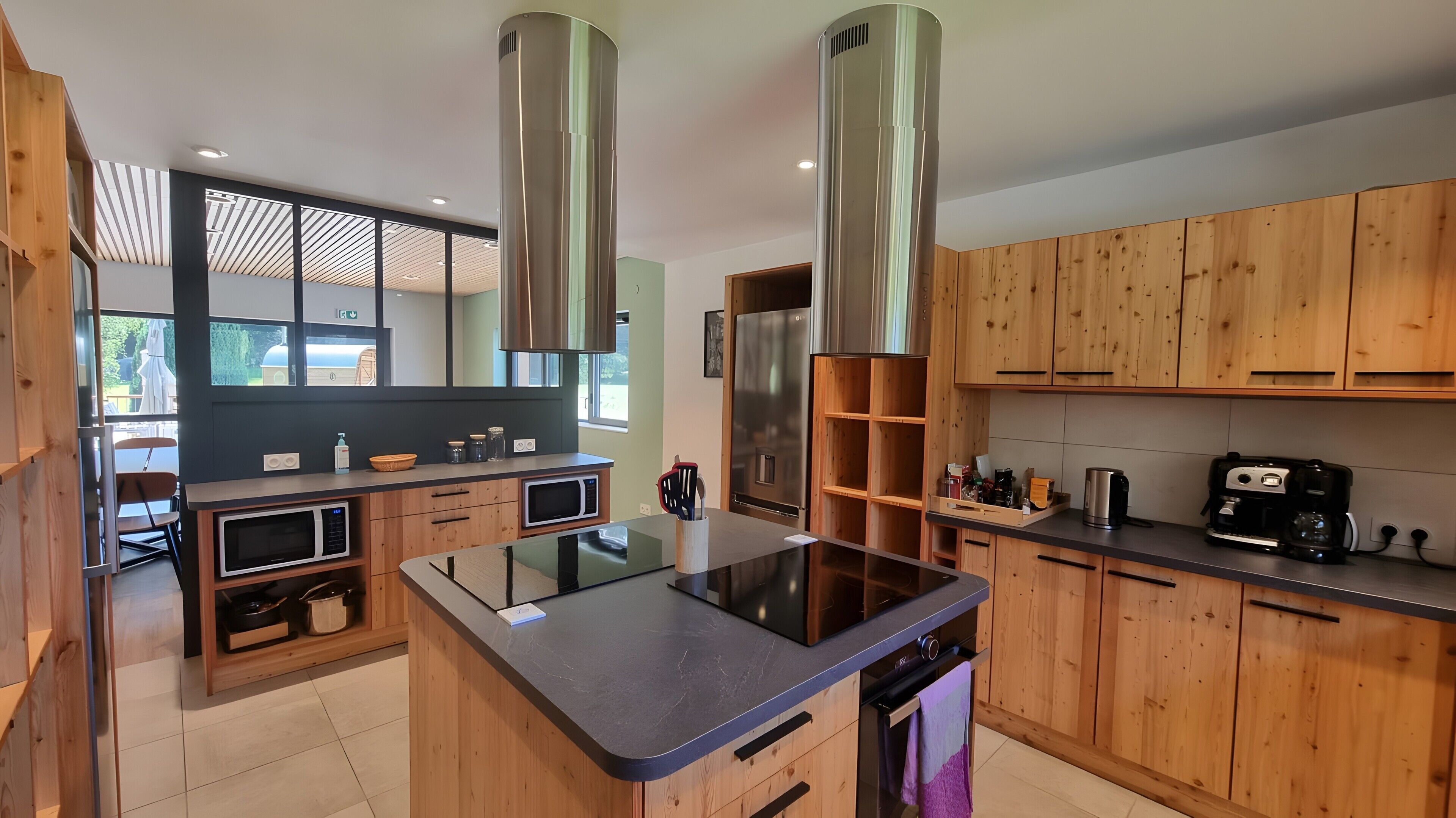 A modern kitchen with wooden cabinets, stainless steel appliances, and a central island.