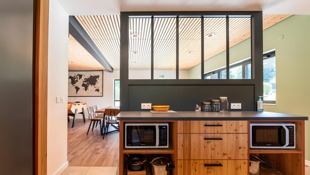 A modern kitchen with wooden cabinetry, built-in microwave, and a large window.