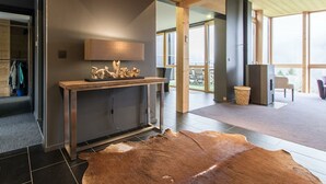 A modern interior with a wooden ceiling, a stone fireplace, and a large leather rug.