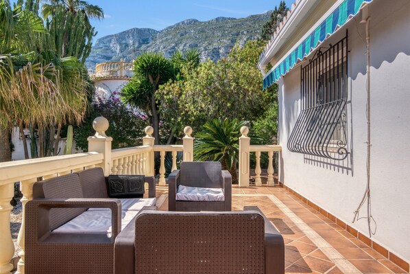 A terrace with wicker furniture, a railing, and a view of mountains.