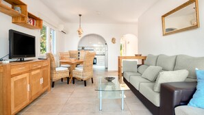 A modern living room with a flat-screen TV, wicker furniture, a glass coffee table, and a sofa. - Holiday Home 'Melodie Delfin' with Mountain View, Wi-Fi and Air Conditioning (Dénia)