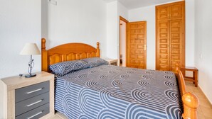 A bedroom with a wooden bed, a bedside table with a lamp, and two wooden doors. - Holiday Home 'Melodie Delfin' with Mountain View, Wi-Fi and Air Conditioning (Dénia)