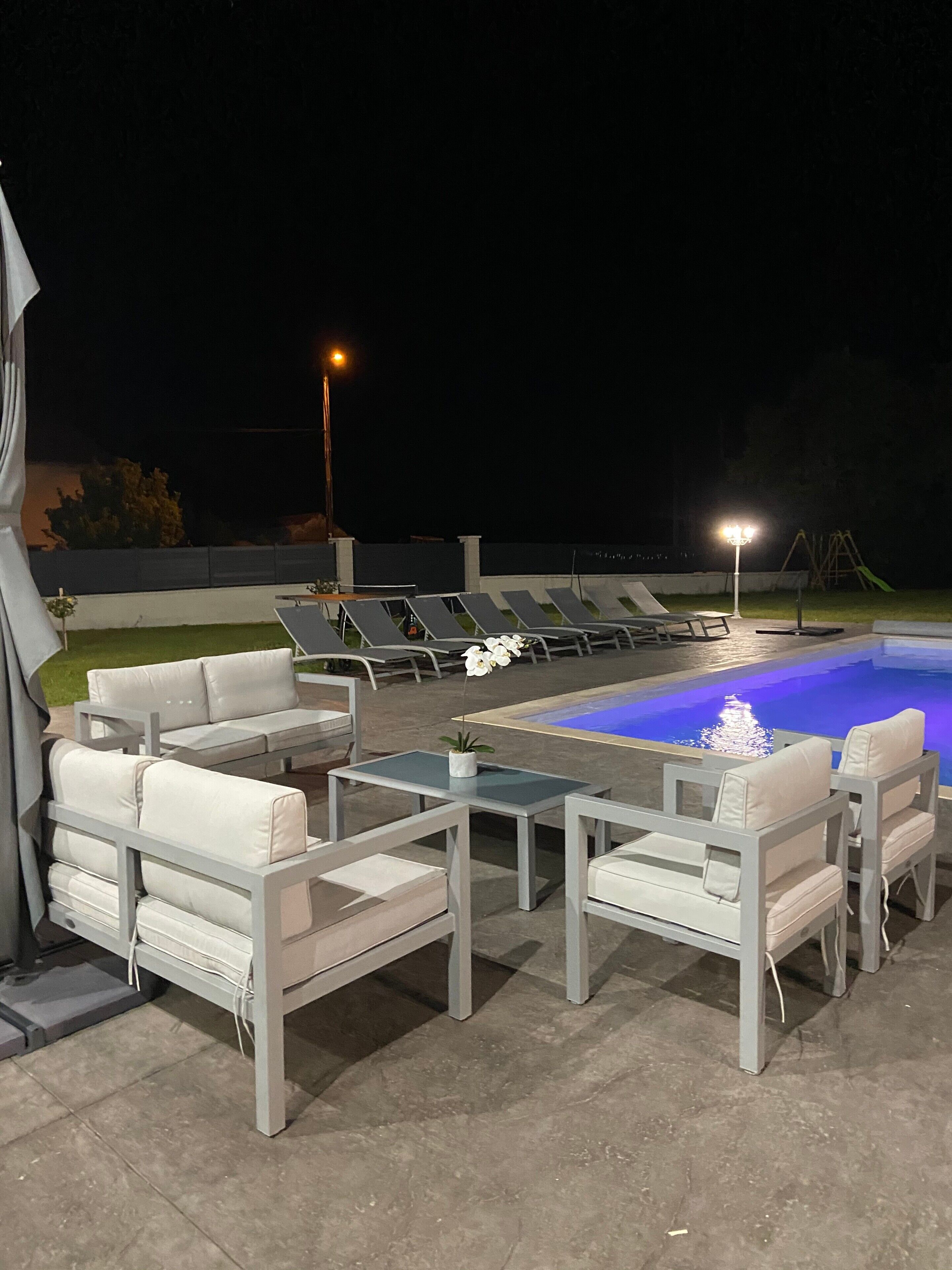 A poolside area with lounge chairs, a table, and a small fountain.