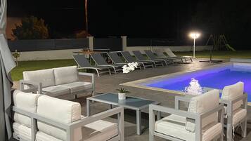 A poolside area with lounge chairs, a table, and a small fountain.
