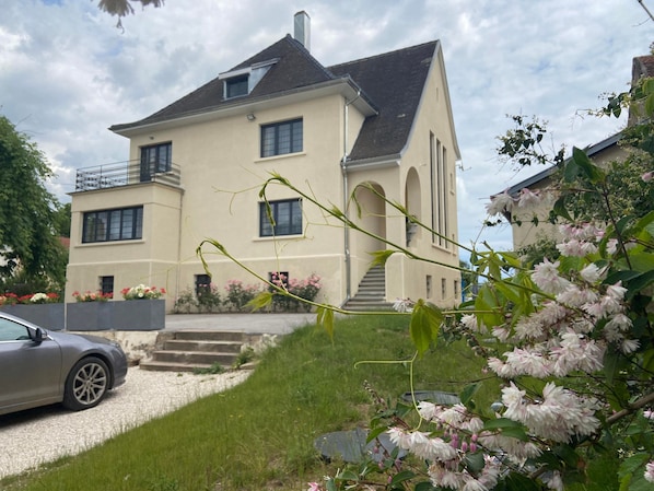 A two-story house with a sloped roof, a visible staircase, and a car parked in the driveway.