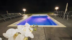 A swimming pool with chairs and a flower arrangement.