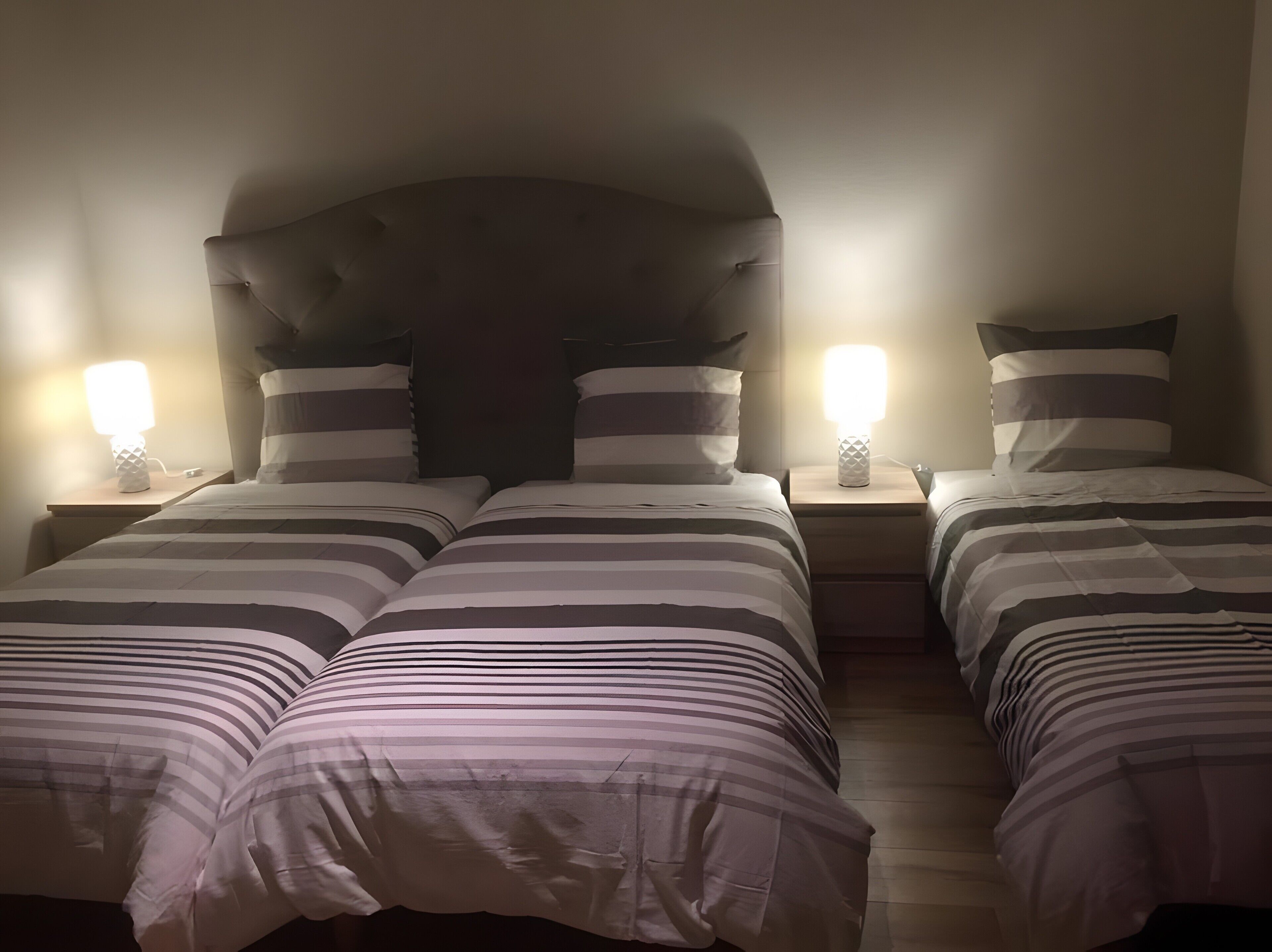 A hotel room with a double bed, two bedside tables, and two wall-mounted lamps.