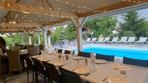 An outdoor dining area with tables set for a meal, overlooking a swimming pool.