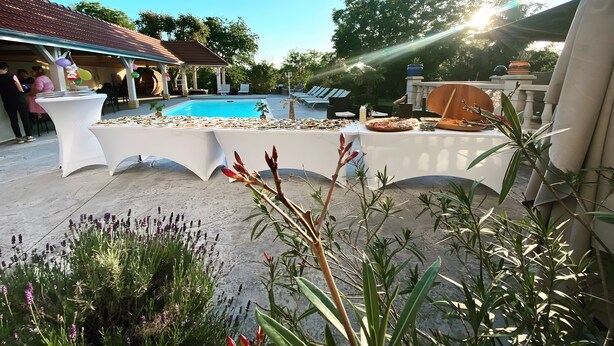 A poolside area with a table set for dining, lounge chairs, and a pergola.