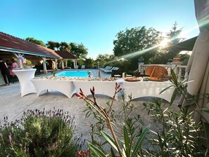 Ein Poolbereich mit Esstisch, Liegestühlen und einer Pergola.