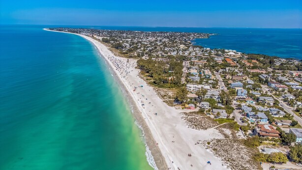 An aerial view of a coastal town with a long sandy beach, clear turquoise waters, and residential buildings. - Renovated 4BR Sarasota Home Private Heated Pool 28-Day Min Near Siesta Key (Sarasota)
