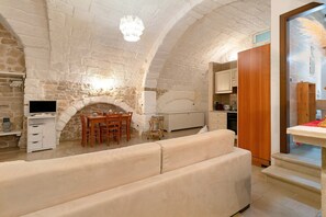 Una stanza con pareti in pietra, un camino, un tavolo da pranzo e un divano.