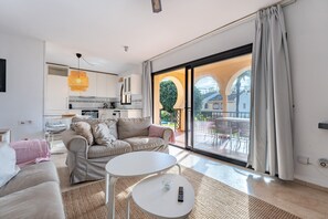 A modern living room with a sofa, a coffee table, and a view of the outdoor patio.