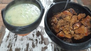 A buffet table with various dishes in black bowls, including a bowl of soup, a bowl of rice, and a bowl of meat. - Pousada Sítio Bicho do Mato  (Tijucas)