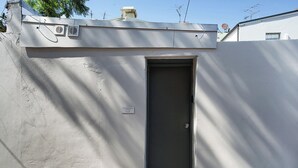 A closed door with a small window, a vent, and a label indicating "42 REDFERN STREET REAR". - Cosy Studio (Redfern)