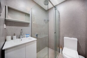 A modern bathroom with a glass-enclosed shower, a white sink with toiletries, and a toilet. - One bedroom  in Australia, Redfern (Redfern)