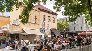 A crowded outdoor seating area with a mural on a building in the background. - Cosy Studio (Redfern)