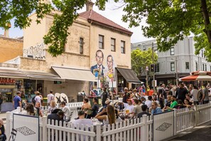 A crowded outdoor dining area with tables and chairs, surrounded by a white fence. - One bedroom  in Australia, Redfern (Redfern)