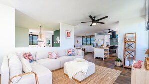 A modern living room with a sectional sofa, a small ottoman, and a large mirror. - Luxury Cliffside Oceanview Villa with Private Pool and Rooftop. Accommodates 7. (Isabela)