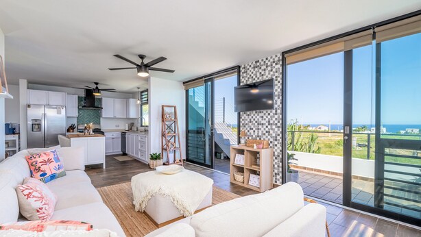 A modern living space with a kitchen, dining area, and a balcony with a view of the sea. - Luxury Cliffside Oceanview Villa with Private Pool and Rooftop. Accommodates 7. (Isabela)