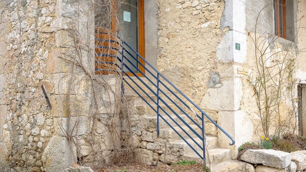 Ein Gebäude aus Stein mit einer Treppe, einer Holztür und einem Fenster.