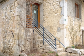 A stone building with a staircase, a wooden door, and a window.