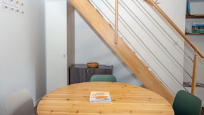 Ein Essbereich mit Holztisch, einem Buch über Pfannkuchen, einer Treppe und einem Bücherregal.