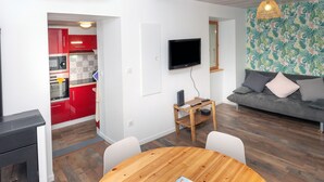 Ein moderner Wohnraum mit einer Küche, einem Essbereich und einer Sitzecke inklusive Sofa und Fernseher.