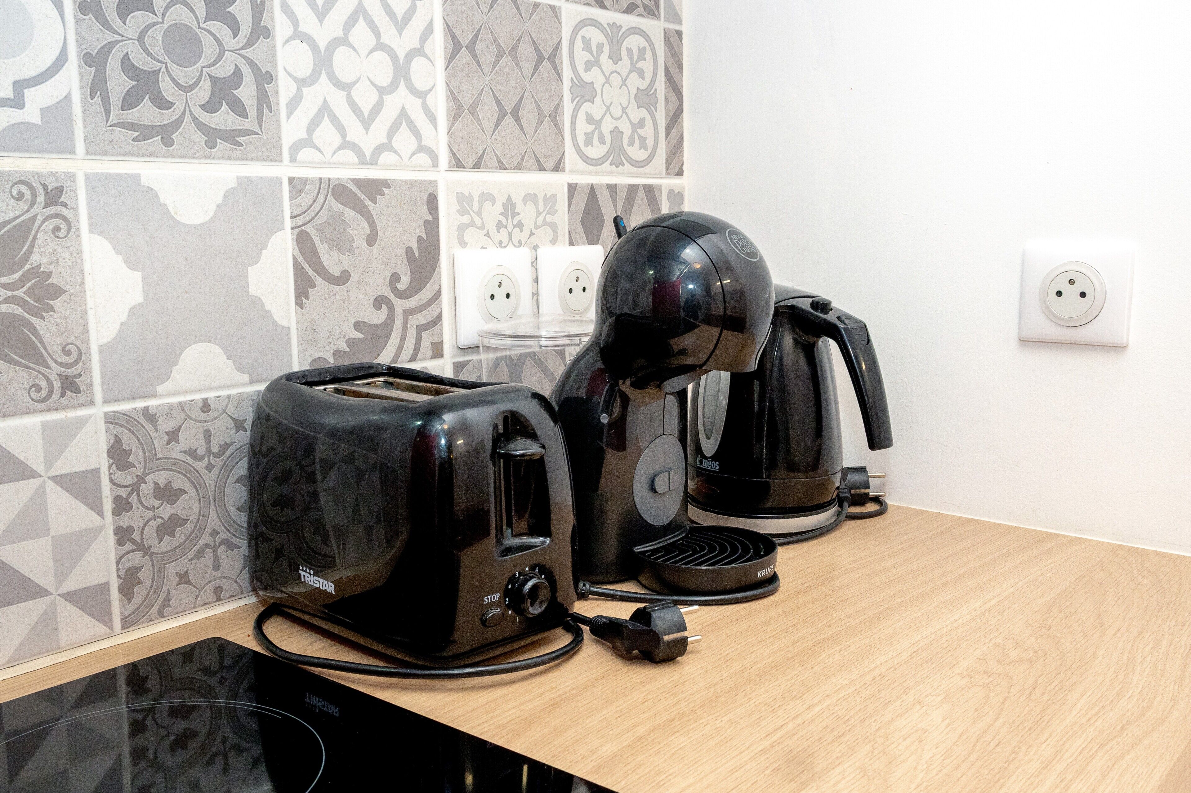 A kitchen with a toaster, a coffee maker, and a power strip on a countertop.