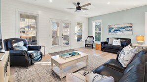 Un salon avec un canapé en cuir noir, une table basse, un fauteuil en cuir noir et un ventilateur de plafond.