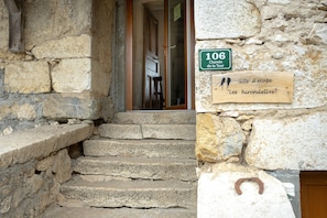 Un escalier en pierre menant à une porte en bois, une enseigne indiquant le numéro de chambre 106 et une plaque en bois portant une inscription.