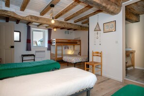 A room with a bunk bed, a single bed, a chair, a window with curtains, and a hanging light fixture. - Apartment 'Les Hirondelles' with Mountain View, Private Terrace and Garden (Saint-Genix-les-Villages)