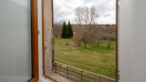 Una habitación con un amplio ventanal que muestra un área verde con árboles y una valla.