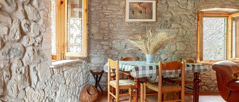 Un comedor rústico con paredes de piedra, muebles de madera y mantel a cuadros.