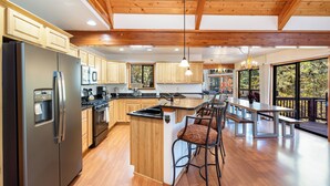 Une cuisine spacieuse dotée de meubles en bois, d’un réfrigérateur en acier inoxydable et d’un grand îlot central avec des tabourets de bar.