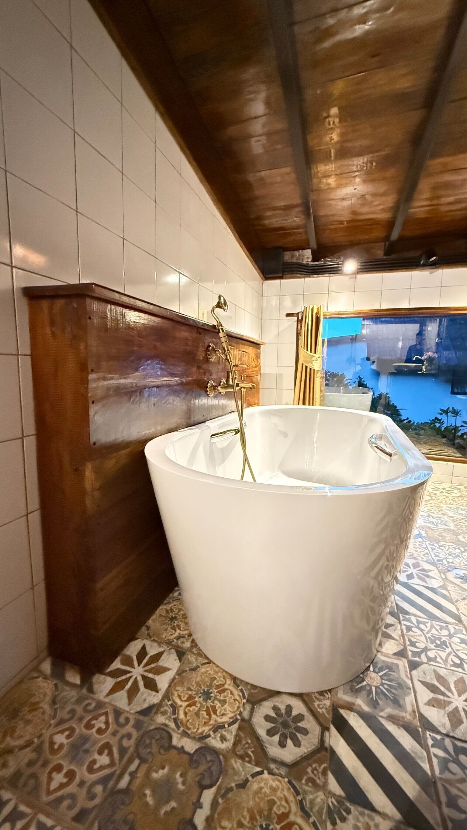 Une salle de bain avec une baignoire sur pieds, des murs carrelés et un sol à motifs.