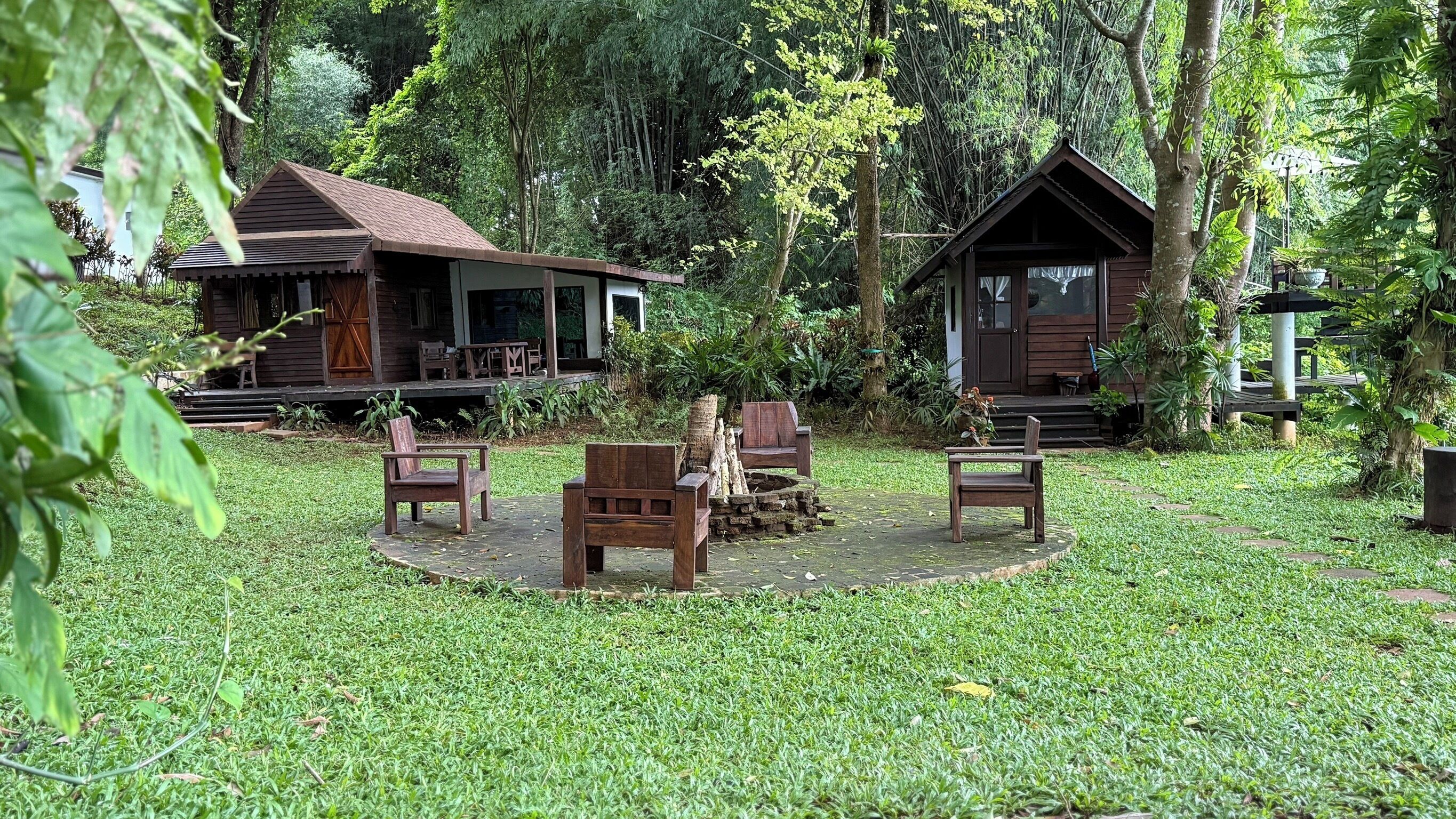 A rustic cabin with a porch, surrounded by lush greenery.