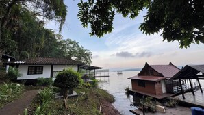 A riverside property with wooden houses, a dock, and a pathway leading to the water.
