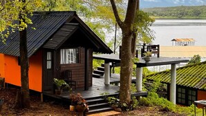 A cabin with a wooden exterior, a deck, and a view of a lake.