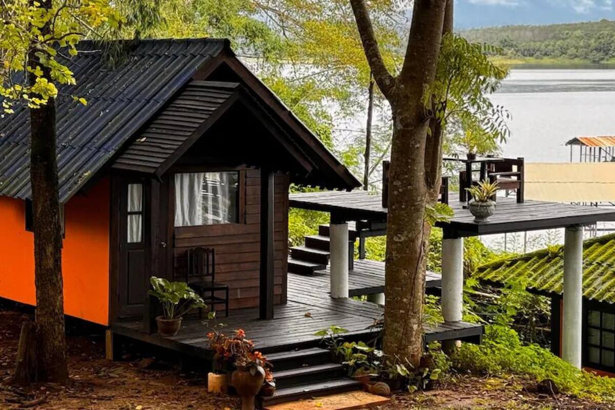 A cabin with a wooden exterior, a deck, and a view of a lake.