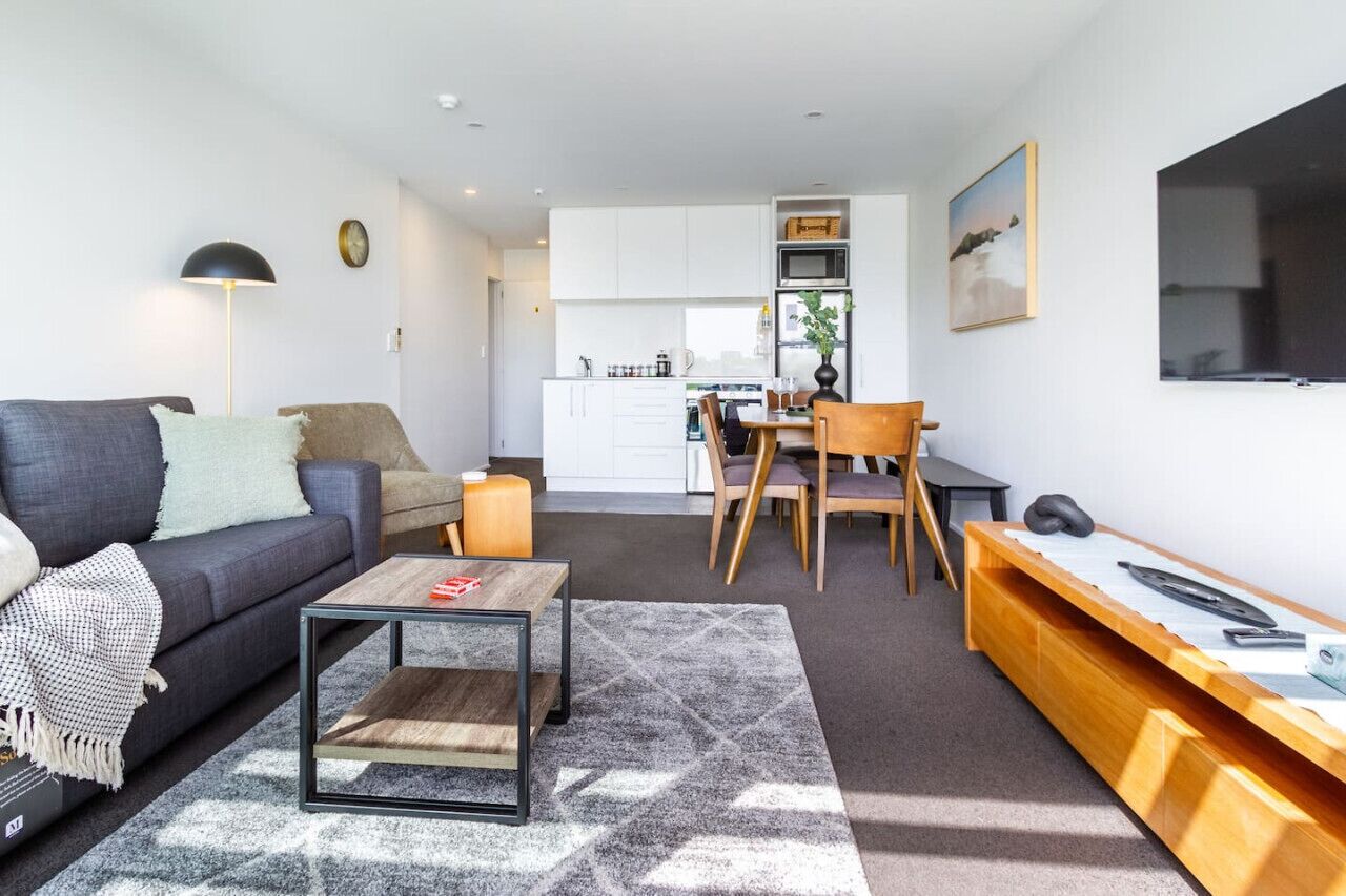 A compact living space with a sofa, coffee table, and a dining area with chairs and a table.