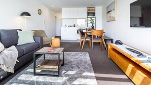 A compact living space with a sofa, coffee table, and a dining area with chairs and a table. - Dashing 2-Bedroom Apartment in Vibrant City Hub (Christchurch)
