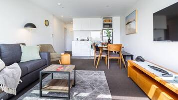A compact living space with a sofa, coffee table, and a dining area with chairs and a table.