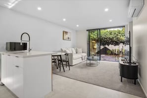 Relax in a spacious living area with a sofa and coffee table, perfect for unwinding. Enjoy a seamless transition to the outdoor space through the sliding glass door.