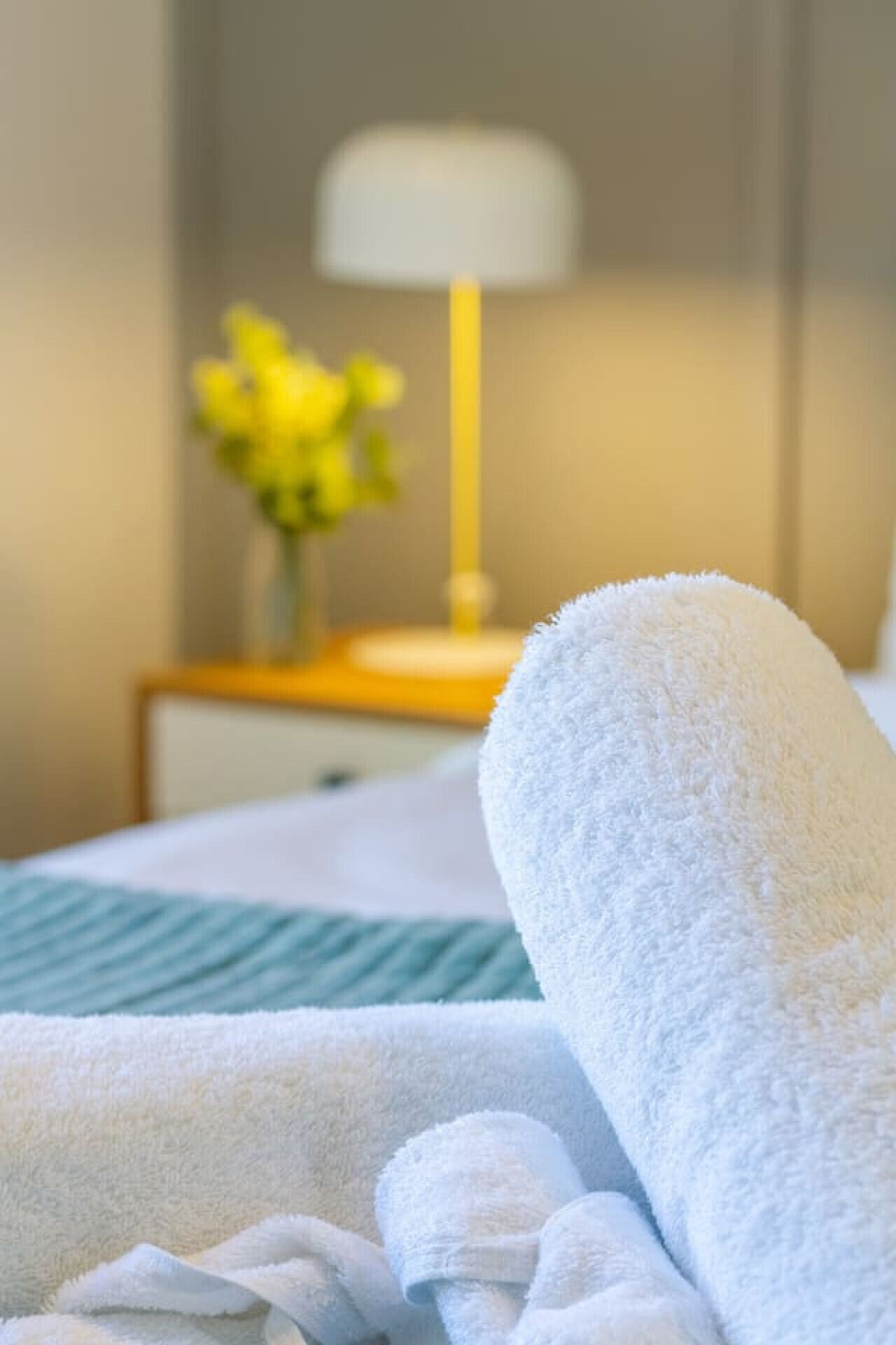 A neatly made bed with white towels and a green striped blanket.