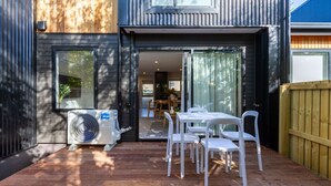 An outdoor deck with a table and chairs, an air conditioning unit, and a wooden fence. - 2 bed 2 bath with Carpark near Canterbury University (Christchurch)