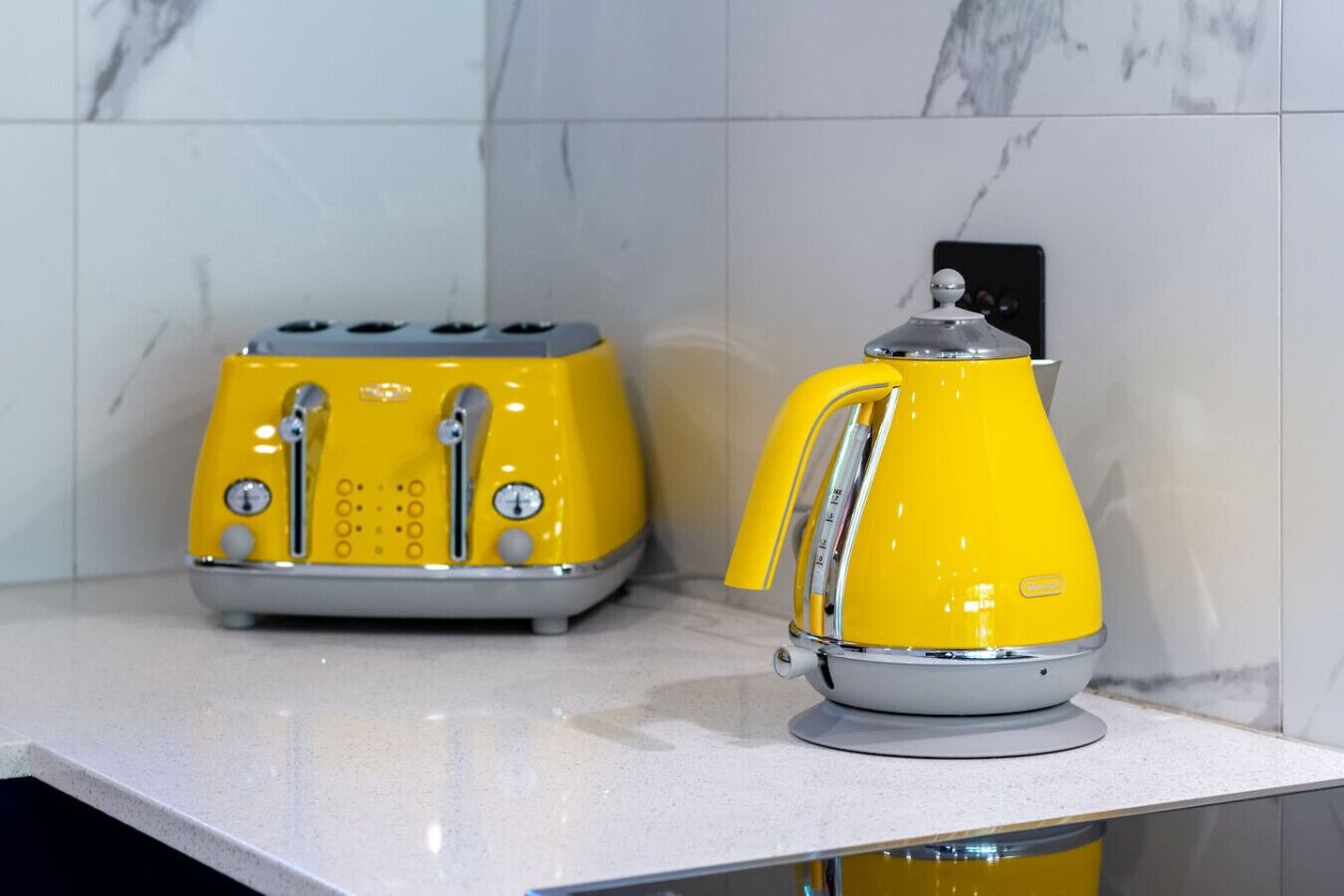 Una cocina con una tostadora amarilla y un hervidor amarillo sobre una encimera blanca.